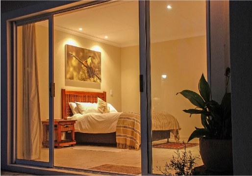 Fourth bedroom seen through sliding doors, with a bed and bedside lamp