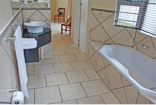 En-suite bathroom with a basin, bath and tiled walls