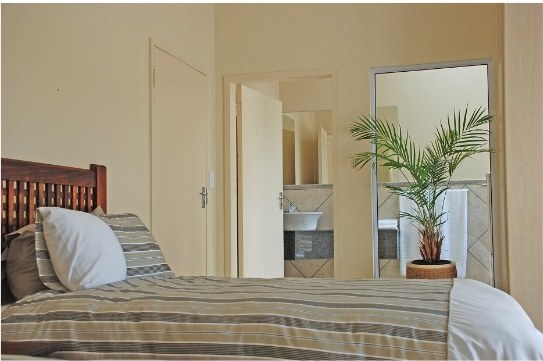 Second bedroom with a bed, mirror and view through to the en-suite bathroom