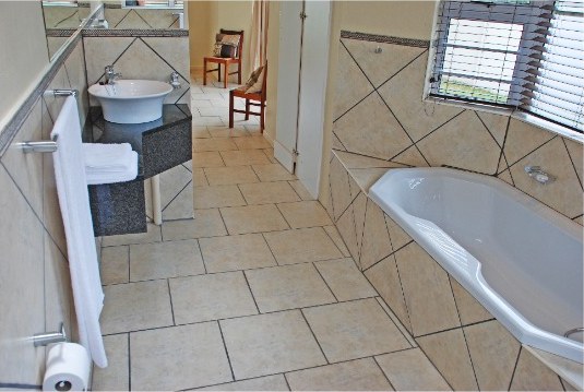 En-suite bathroom with a basin, bath and window